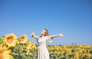 Naklejka na ściany i meble Beauty sunlit woman on yellow sunflower field Freedom and happiness concept. Happy girl outdoors