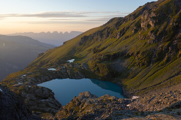 Fototapeta na wymiar A wonderful view to the horizon at a beautiful sunset in the alps of Switzerland by an alpine lake called Schottensee. These colors by the sunset are just amazing. Epic clear blue water.