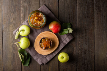 Tasty homemade apple jam, confiture in a glass jar with apples on a black wooden table