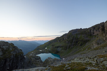 A wonderful view to the horizon at a beautiful sunset in the alps of Switzerland by an alpine lake called Schottensee. These colors by the sunset are just amazing. Epic clear blue water.