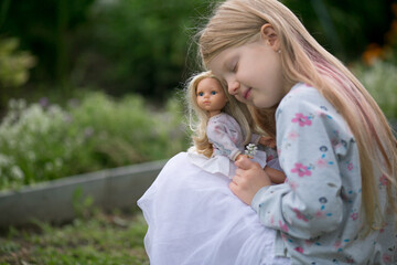 маленькая девочка с любимой куклой в саду парке 
little girl with her favorite doll in the garden park