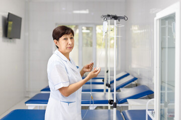 Central Asian senior nurse ready to put saline drip