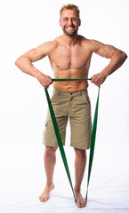 Fototapeta premium muscular man in shorts shakes muscles or poses with an elastic band for fitness. grey background