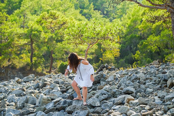 one beautiful red-haired girl walks barefoot on the stones near the forest. sexy woman at resort.