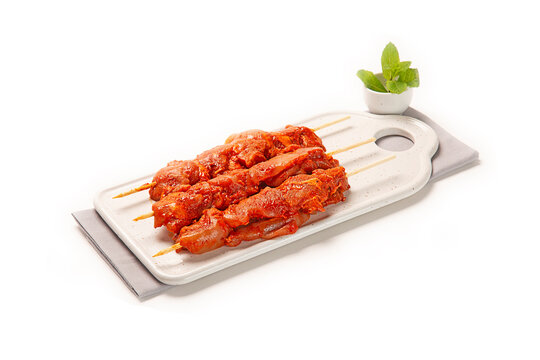 pinchos morunos de cerdo pollo adobado fresco crudo sobre plato blanco con servilleta de tela gris, aislado fondo blanco