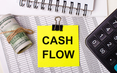 On the desktop there are reports, notepads, a calculator, a cash and a yellow sticker with the text CASH FLOW. Business concept