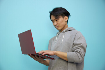 ノートパソコンと灰色のパーカーの日本人男性