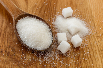 Sugar in wooden spoon, on wooden table