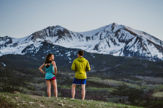 Two friends catch their breath while running in front of large peak
