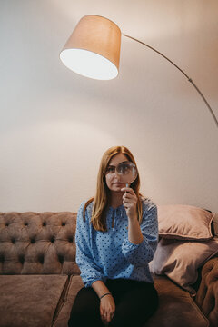 woman holding magnifying glass at home bored