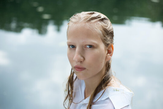 Blonde teenage girl face portrait with wet hair by the pond