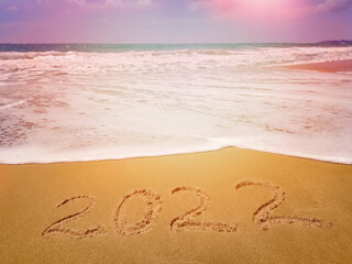 The numbers 2022 are written on the sandy beach against the background of the sea, ocean. Happy New Year and Vacation!