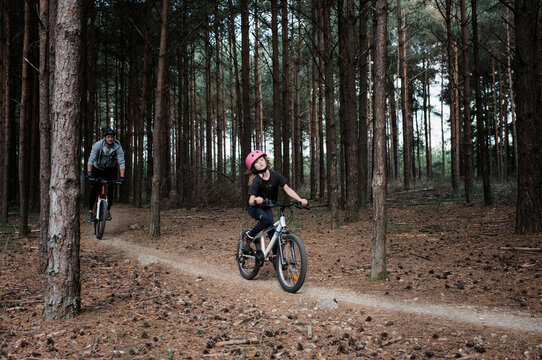 dad and daughter riding their bikes through a forest