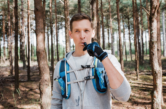 man drinking from a bladder in his running vest whilst in the forest