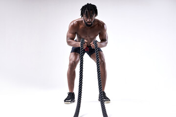 Muscular man working out with heavy ropes isolated on white studio background. Handsome man with...