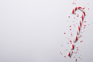 Broken sweet Christmas candy cane on white background, top view. Space for text