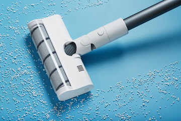 The turbo brush of the vacuum cleaner cleans white balls, top view on a blue background. The...