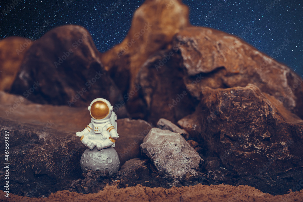 Wall mural Astronaut wearing white space suit and helmet and meditating while sitting on the moon.