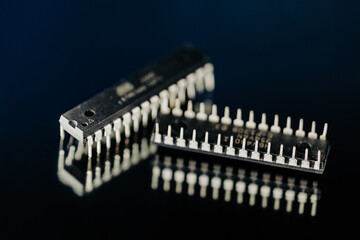 DIP microchips electronic components on dark blue mirror macro shot.