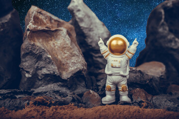 Astronaut raising arms while standing on rocky mountain.Concept of cosmonautics, space travel, freedom and winning.