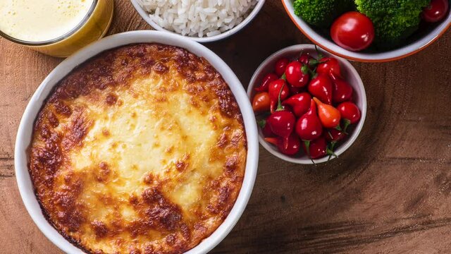 Shepherd's pie. (Escondidinho) Dish coming out of smoke. Slide shot.