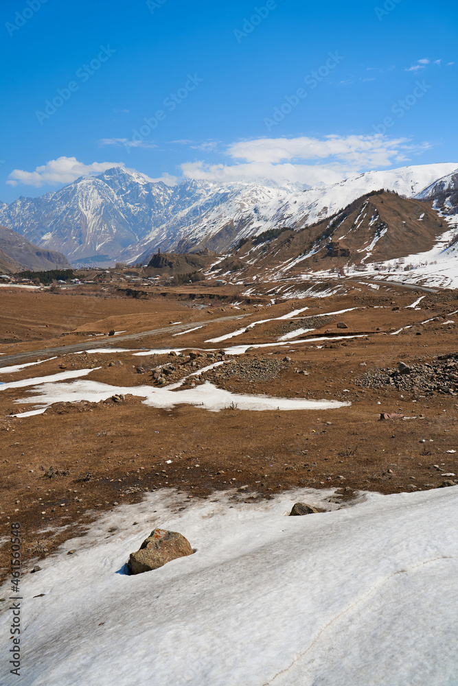 Wall mural In a mountain valley, a breathtaking landscape of giant covered mountains in the background