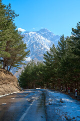 Automobile mountain road in spring with a breathtaking view of the mountain with a snow cap on top
