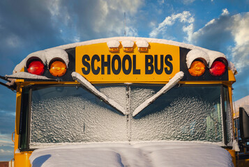 The front of a school bus after a fresh winter snowfall.
