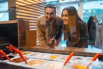 Friends are choosing cakes from showcase in pastry shop. Selective focus