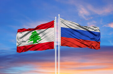 Russia and Lebanon two flags on flagpoles and blue cloudy sky