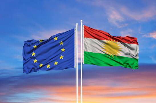 European Union and Kurdistan two flags on flagpoles and blue cloudy sky
