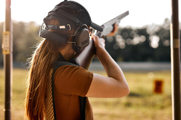 Young caucasian woman on tactical gun training classes. Woman with weapon, wearing cap, protective...