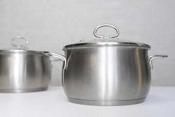 Stainless steel pots, stockpots on white table, eco friendly kitchen utensils without harm, harmless safe for people