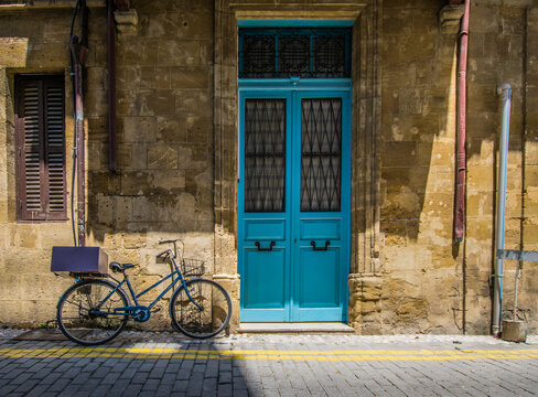 Blue bicycle next to Blue tall traditional Greek door of a stone house in Cyprus