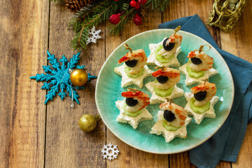 Festive snack of canapes on the Christmas table. Canapes with cheese, cucumber and shrimps. Copy space.