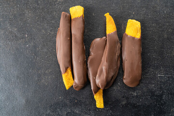 Dried mango pieces in chocolate. Mango dried fruit sticks are doused with milk chocolate on black background