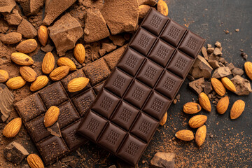 Store Cooking chocolate bars with almonds handmade sweets. Composition of bars and pieces of dark almond chocolate on a black background, top view. Pastry craft on the table