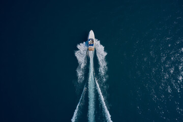 White speed boat fast movement on the water top view. Travel - image. Top view of a white high-speed boat. Boat movement on blue water top view.