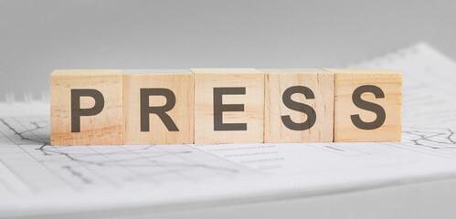 press is written on light wooden blocks. the word is located on a sheet with charts and graphs