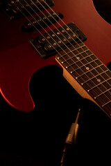 Part of a red electric guitar on black background. Close-up view of guitar fretboard and pickups.