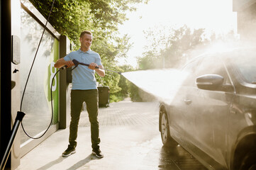 Man holds high pressure water gun, car wash