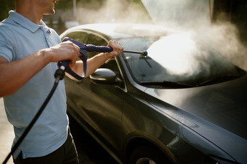 Man holds high pressure water gun, hand car wash