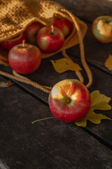 Crocheted yellow bag with red apples on a wooden table. Autumn harvest.