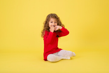 Portrait of a little curly girl on a yellow background