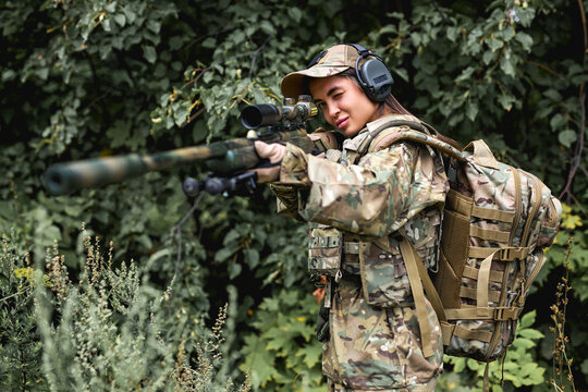 young slender caucasian woman soldier in military gear shooting with rifle machine gun in wild forest field, female army nature outdoor military combat training, aim weapon at target.femme fatale.