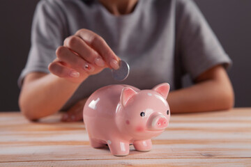 Obraz na płótnie Canvas woman putting money savings inside of piggy bank