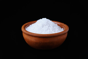 Sea salt crystals in brown crockery against black background. Mineral bath rock salt.