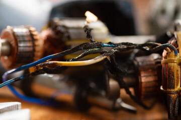 Burnt wires on the parts of an electrical appliance, drills on a wooden table in a repair shop....