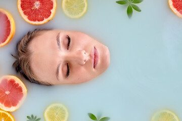 Top view on sleepy calm woman taking bath with milk and citrus, relaxing in romantic atmosphere, beauty cosmetic salon and spa for woman. Close-up lady with natural make-up, portrait