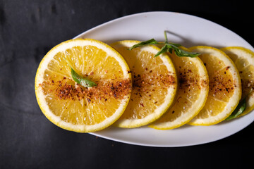 Plate of orange slices with chili powder on black surface